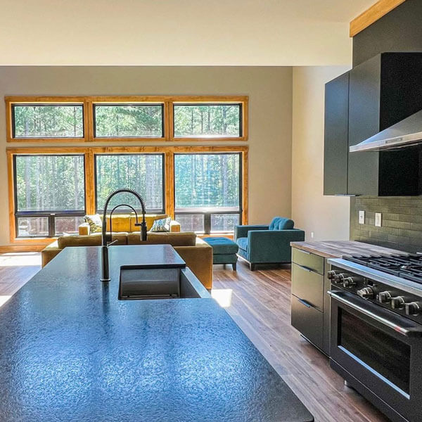 kitchen overlooking living room with large windows and a view of the forest