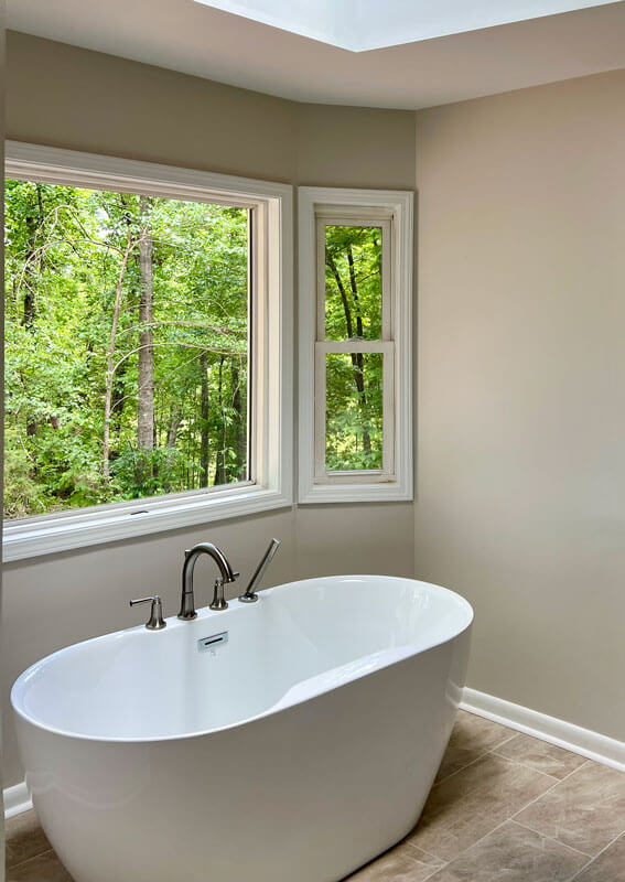 soaking tub next to 3 pane window overlooking woods