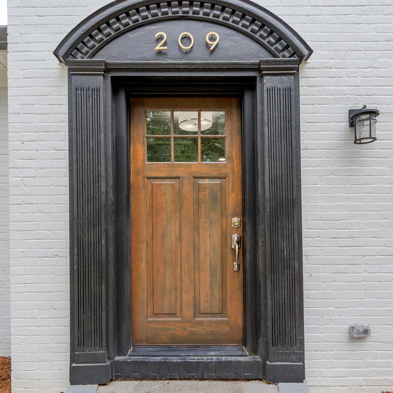 front door to a home that is wood and black arch